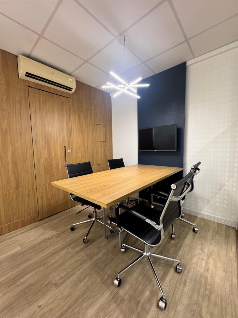 Sala de reunião do escritório da Concepção Arquitetura, com mesa de madeira e painel azul