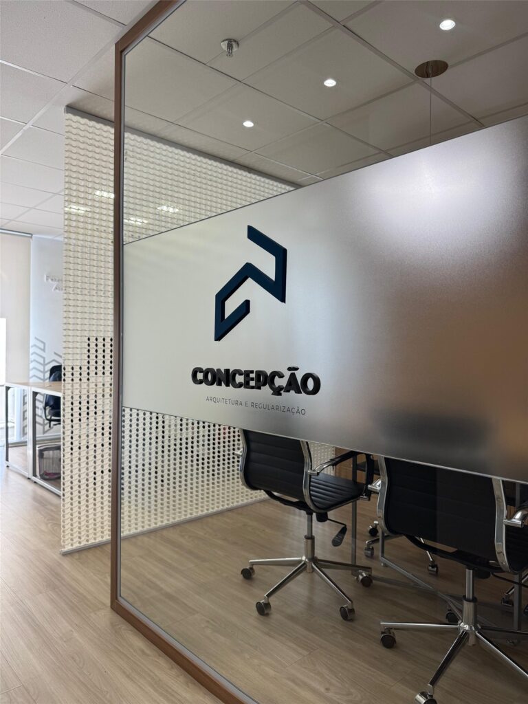 Sala de reunião do escritório da Concepção Arquitetura e Regularização com o logotipo no vidro